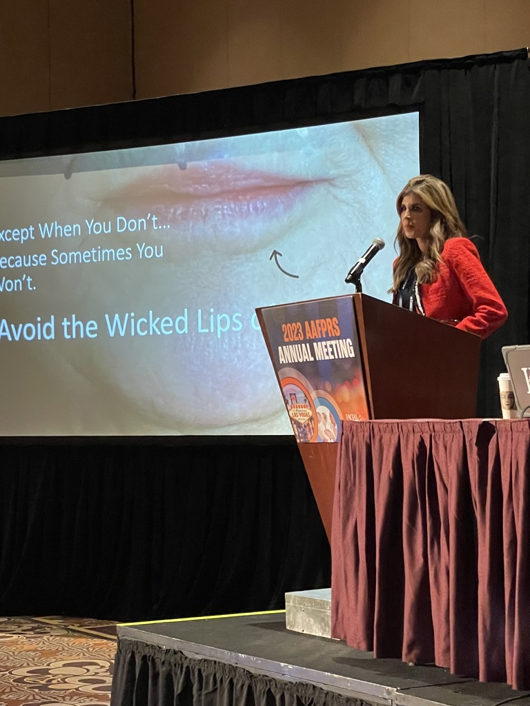 Melanie Petro presenting at the 2023 AAFPRS Annual Meeting with a lip photograph on the screen.